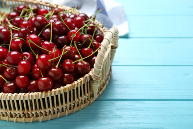Photo of Sweet juicy cherries on light blue wooden table, closeup. Space for text