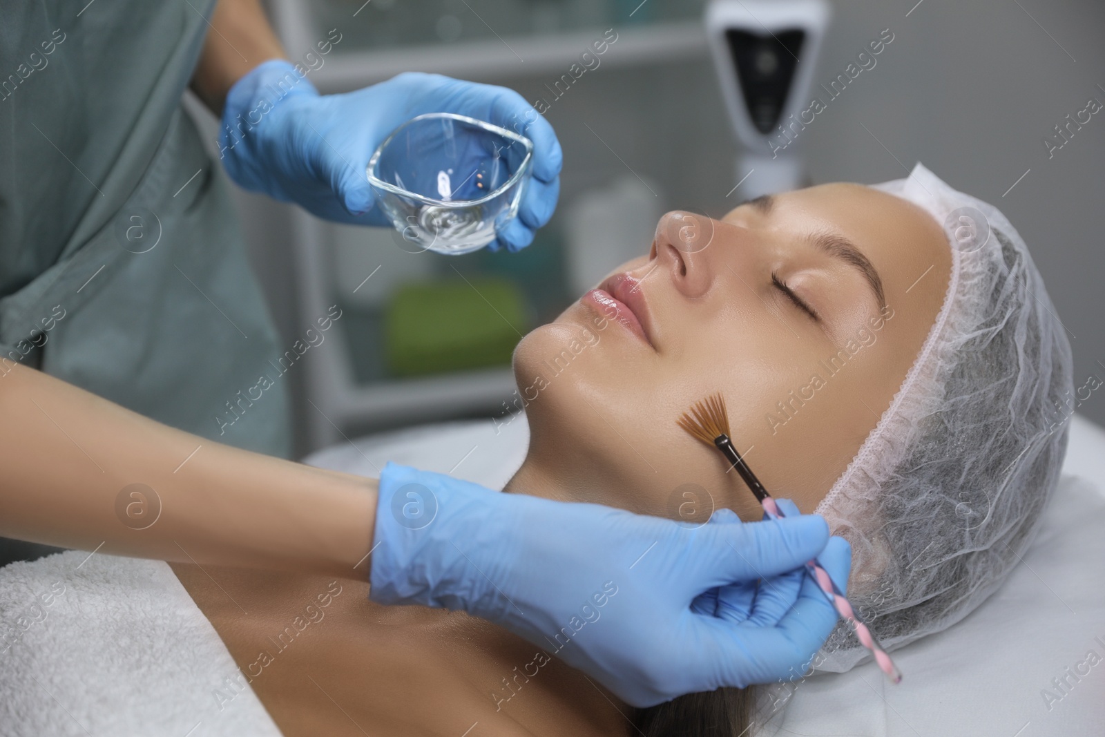 Photo of Cosmetologist applying chemical peel product on client's face in salon