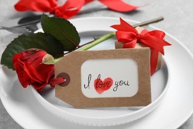 Photo of Beautiful place setting with gift box and flower on table, closeup. Valentine's day romantic dinner