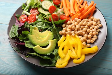 Balanced diet and vegetarian foods. Plate with different delicious products on light blue wooden table, closeup