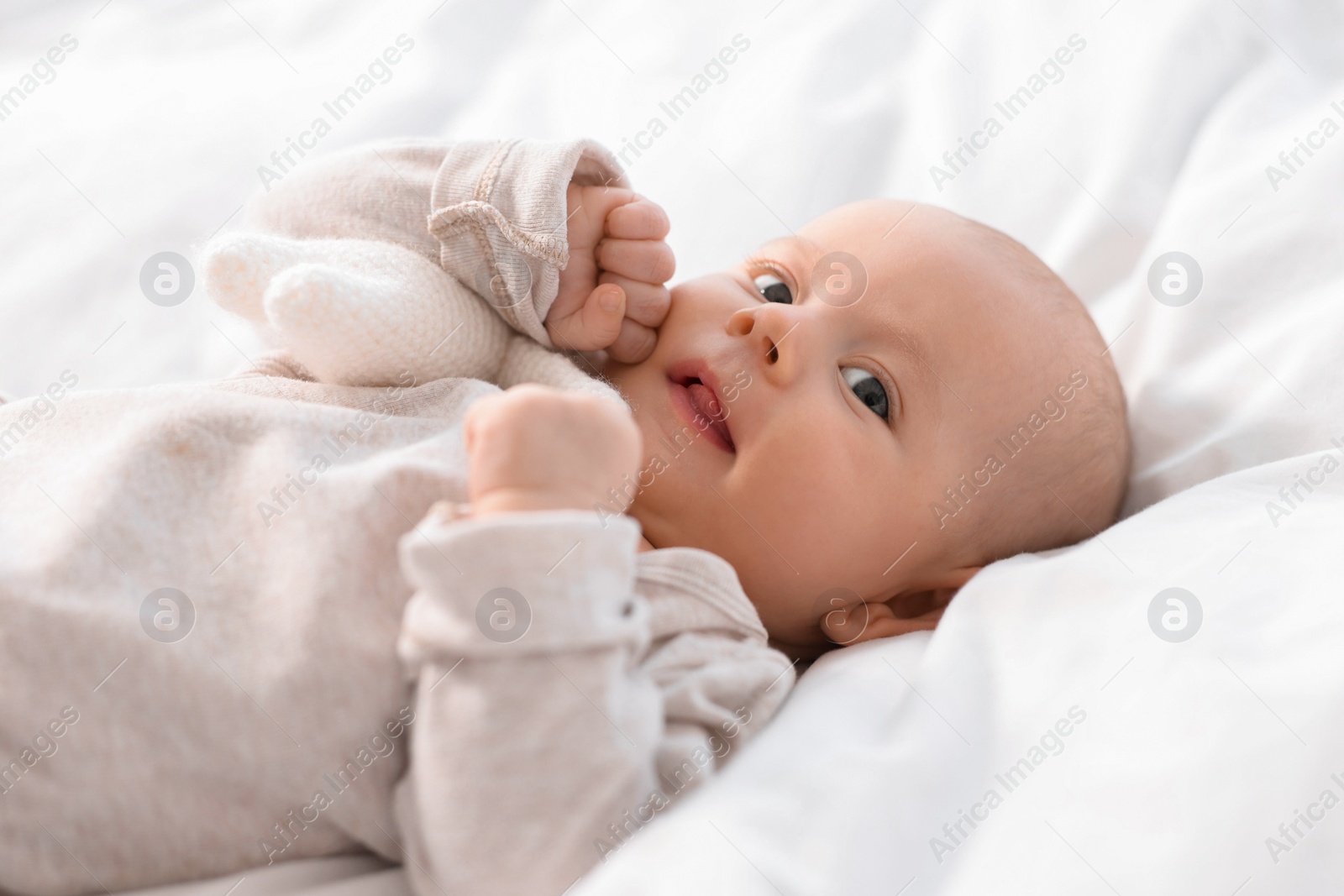 Photo of Cute little baby lying on white sheets