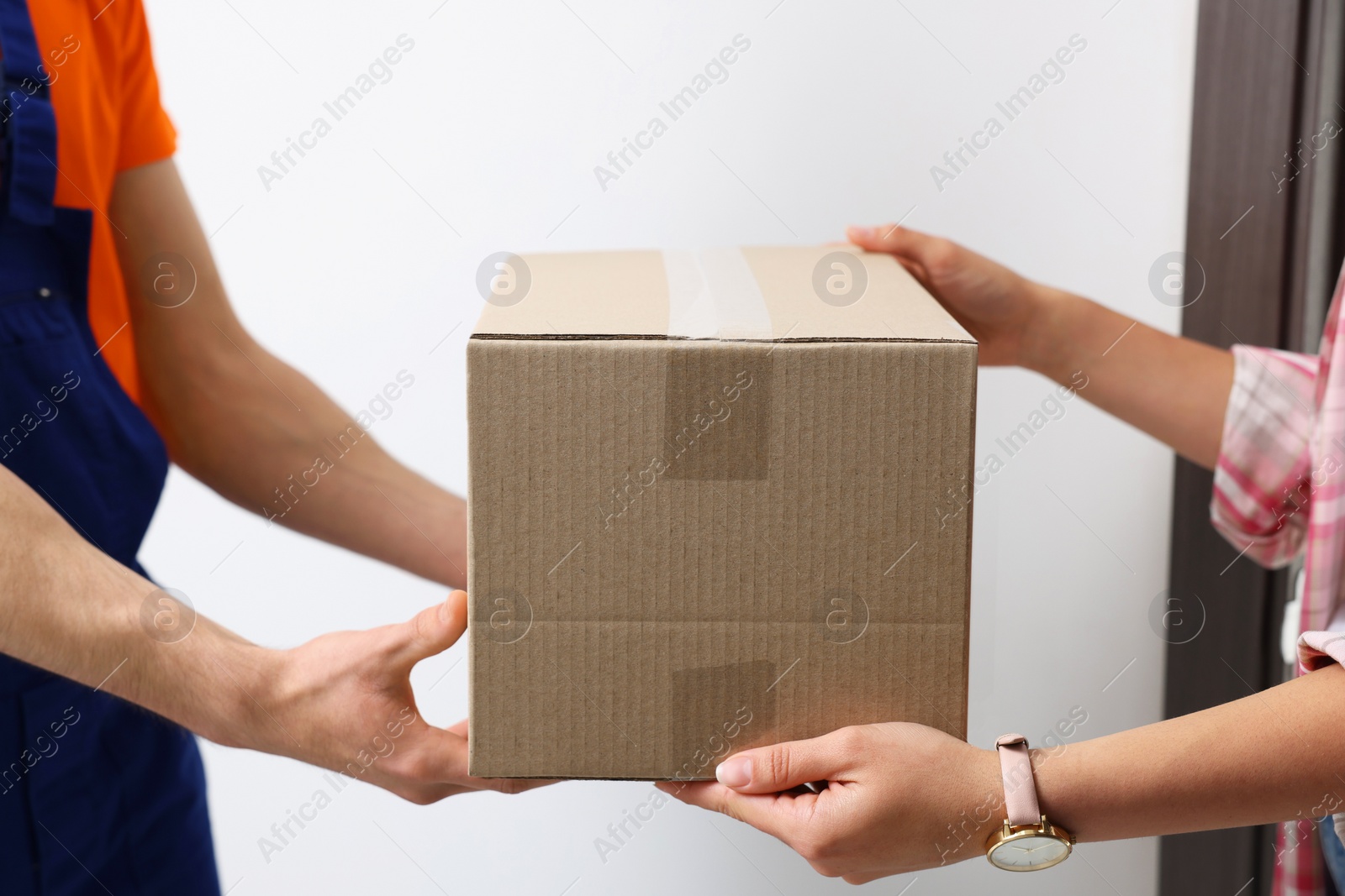 Photo of Woman receiving parcel from courier at home, closeup