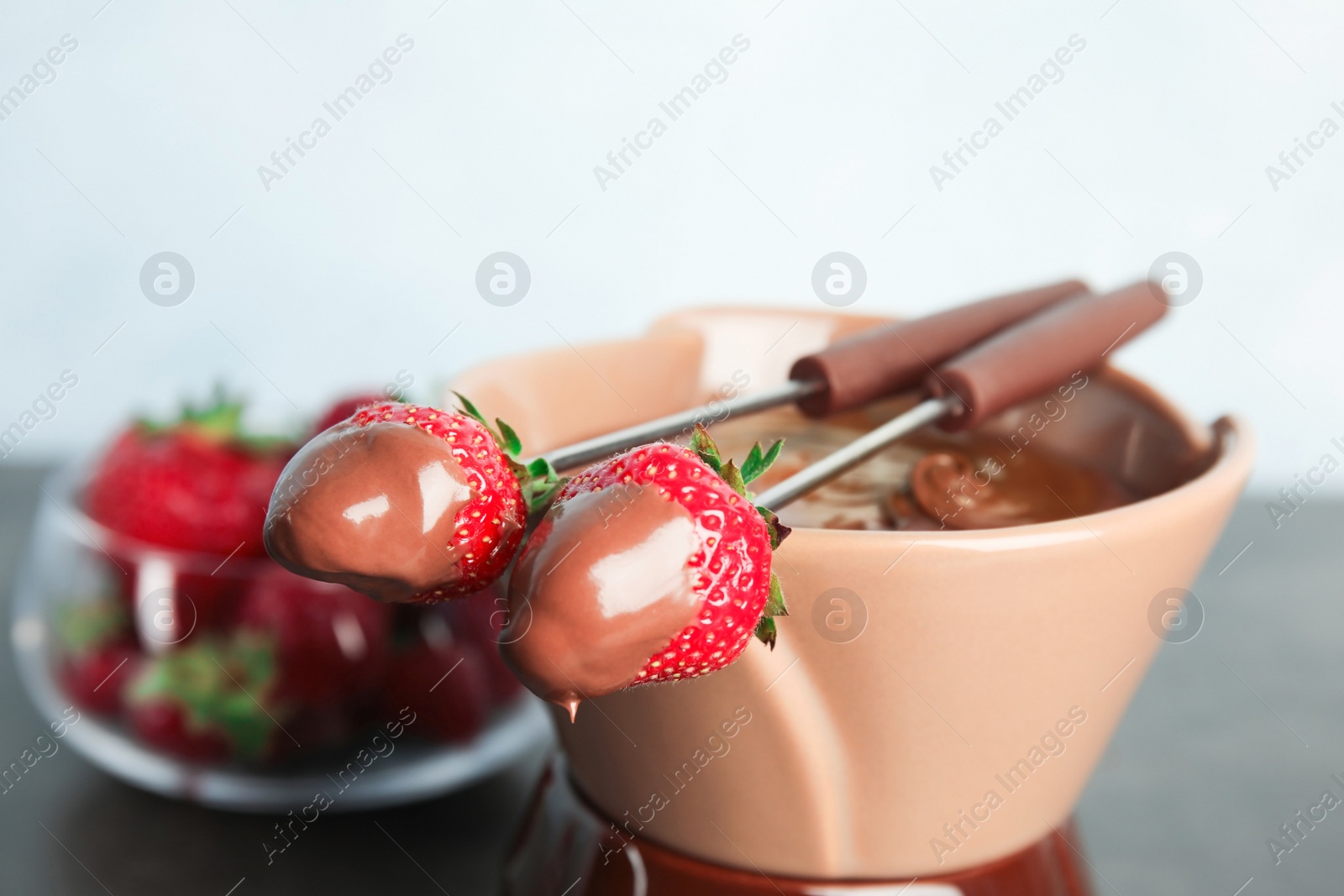 Photo of Ripe strawberries dipped into chocolate fondue, closeup