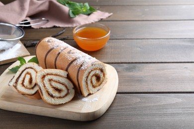 Photo of Tasty cake roll with jam on wooden table, space for text