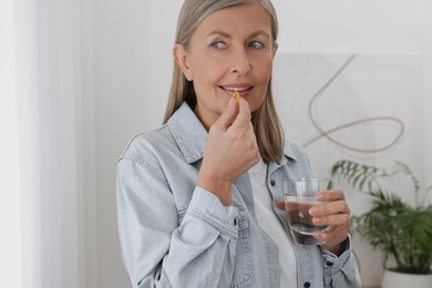 Beautiful woman taking vitamin pill at home