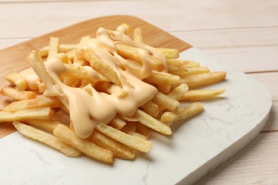 Delicious french fries with cheese sauce on wooden table, closeup