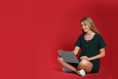 Young woman with laptop on red background. Space for text