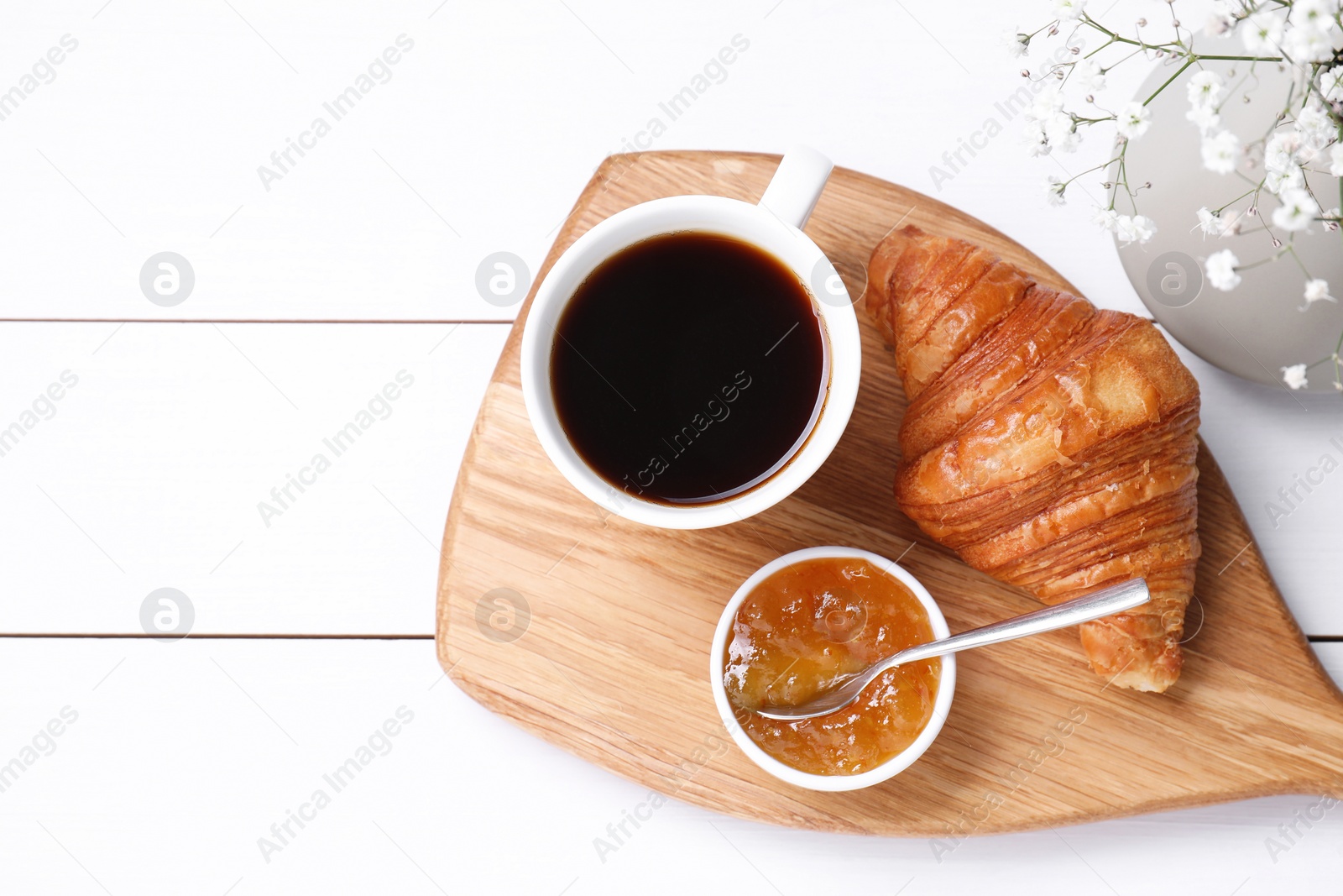 Photo of Tasty breakfast. Cup of coffee, jam and croissant on white wooden table, top view. Space for text