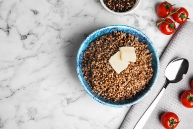 Flat lay composition with bowl of buckwheat porridge served on white marble table. Space for text