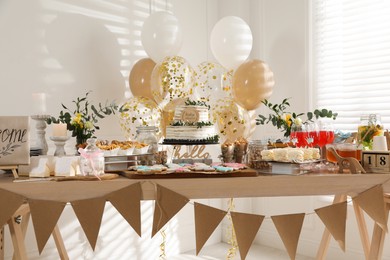 Photo of Baby shower party. Different delicious treats on wooden table and decor indoors