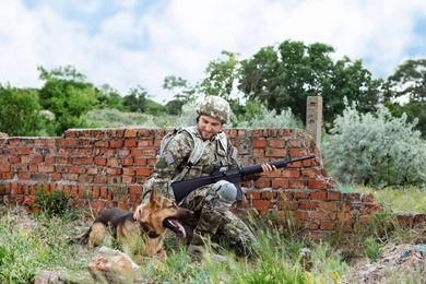 Photo of Man in military uniform with German shepherd dog at firing range