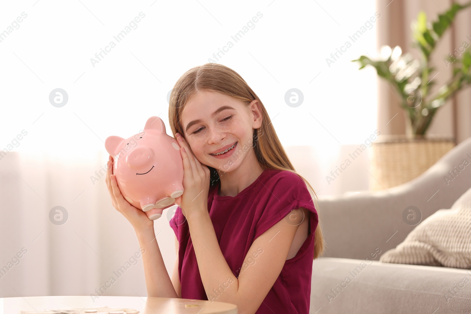 Photo of Teen girl with piggy bank at home