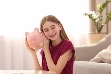 Teen girl with piggy bank at home