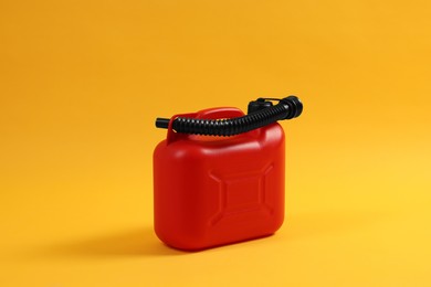 Red plastic canister with tube on orange background