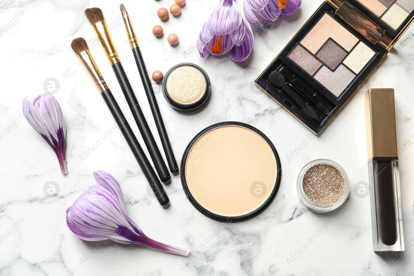 Photo of Many different makeup products and spring flowers on marble background, flat lay