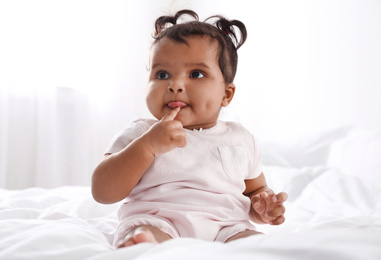 Photo of Cute African American baby on bed at home