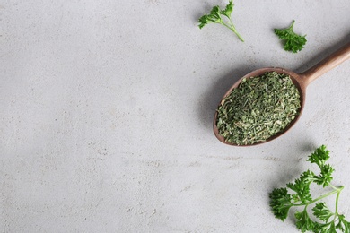 Photo of Spoon with dry parsley and space for text on grey background, top view