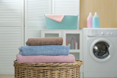Photo of Fresh towels on wicker basket in laundry room