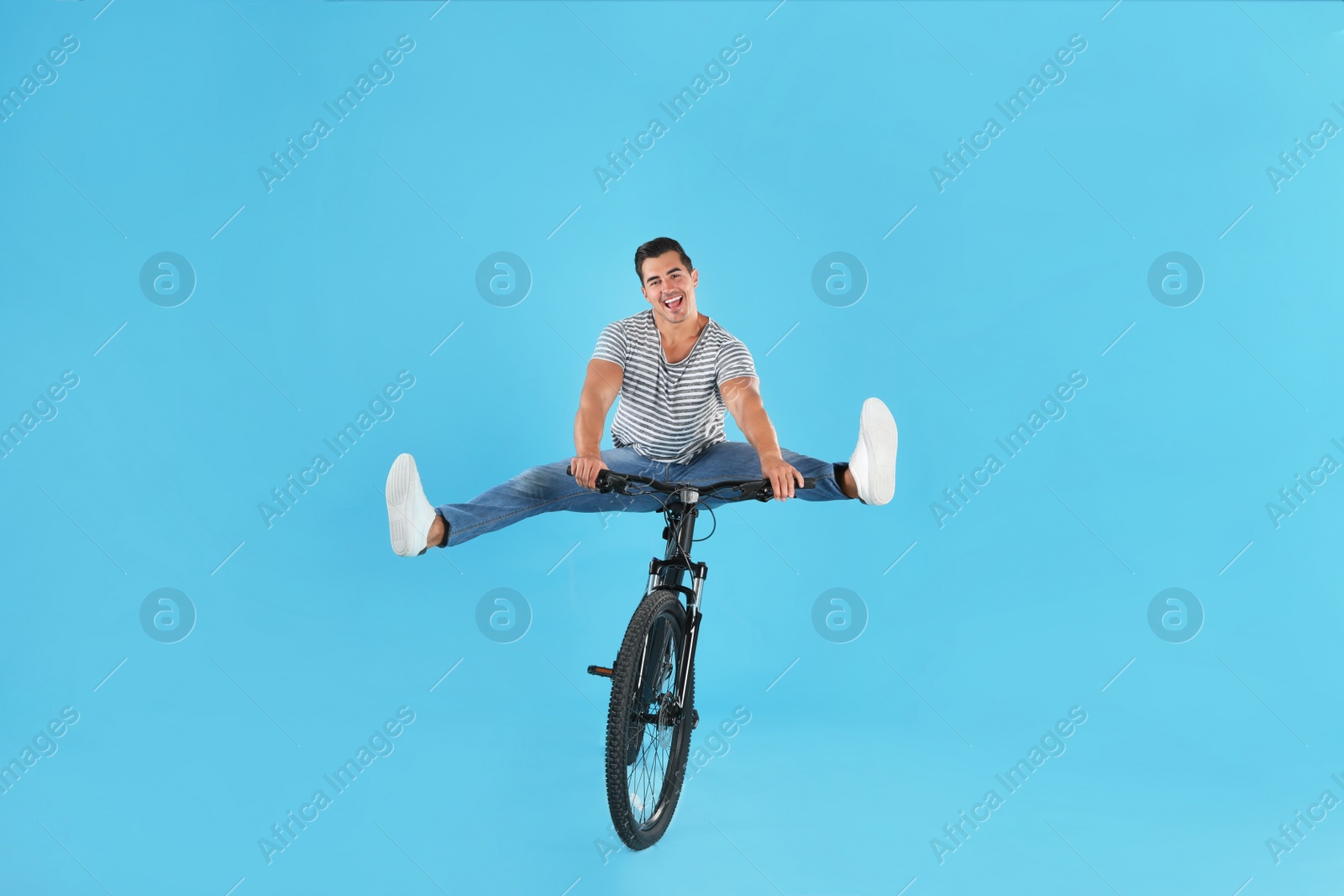 Photo of Handsome young man with modern bicycle on light blue background