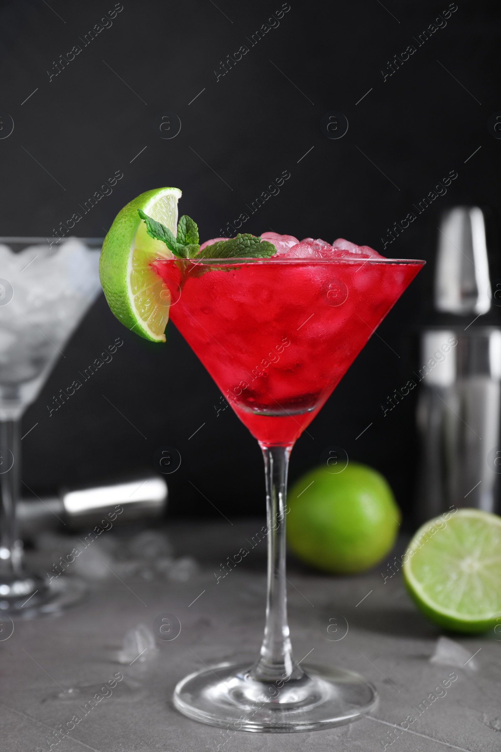 Photo of Tasty red alcoholic cocktail in martini glass on light grey table