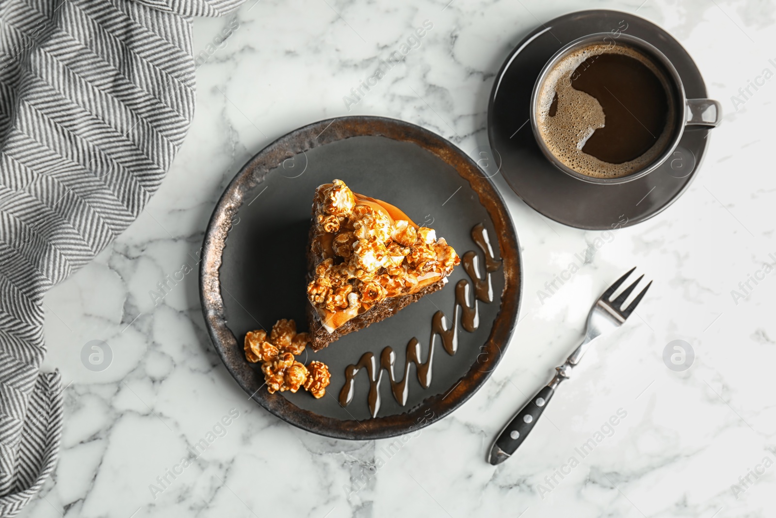 Photo of Piece of delicious homemade cake with caramel sauce and popcorn on table, top view