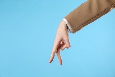 Businesswoman imitating walk with hand on light blue background, closeup. Finger gesture