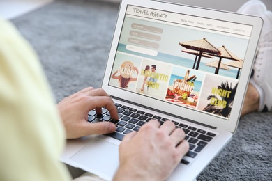 Man booking tickets online indoors, closeup. Travel agency concept