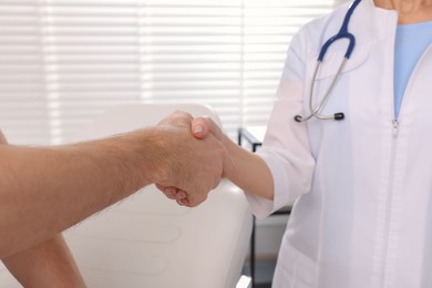 Photo of Doctor shaking hands with patient in clinic, closeup