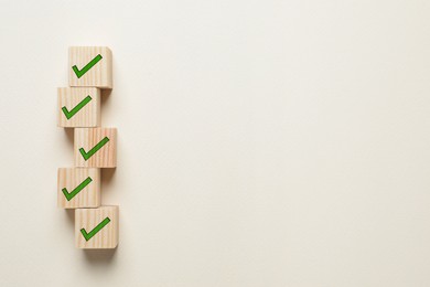 Wooden cubes with check marks on beige background, flat lay. Space for text