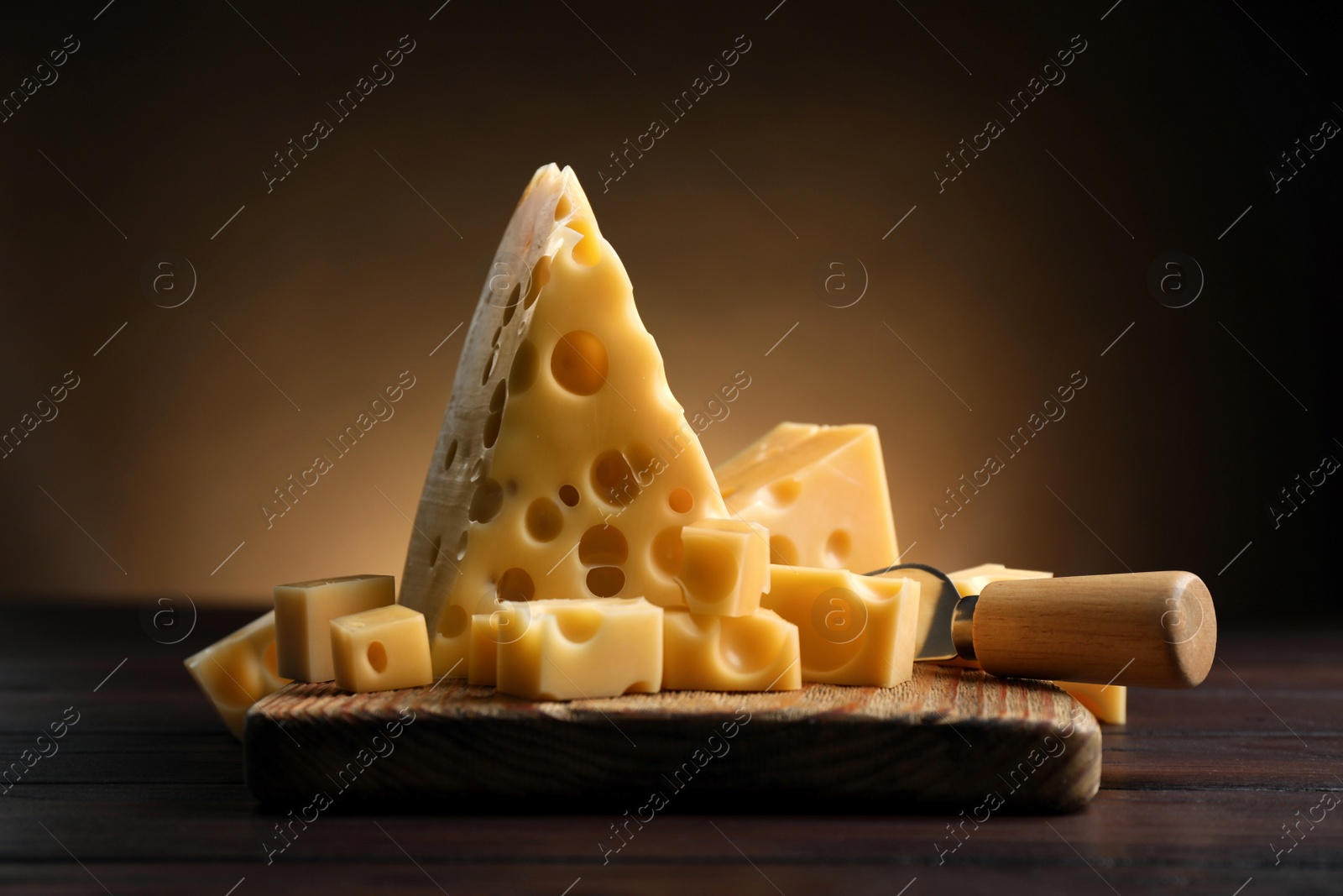 Photo of Pieces of delicious cheese and knife on wooden table