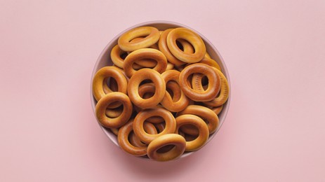 Bowl of tasty dry bagels (sushki) on pink background, top view