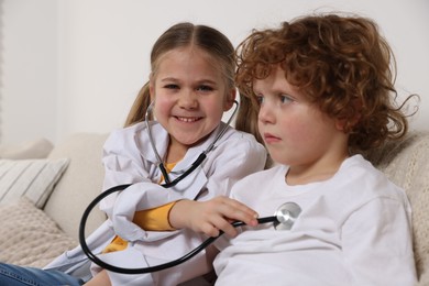 Little girl playing doctor with her friend at home