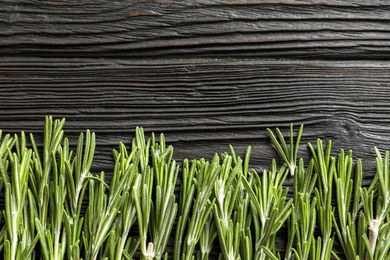 Photo of Fresh rosemary twigs on wooden table, top view