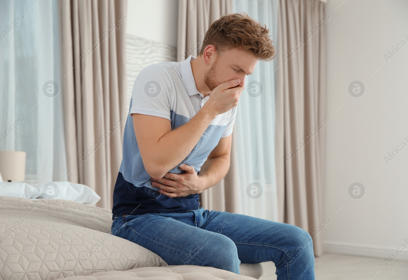 Photo of Young man having nausea in bedroom. Feeling  sick