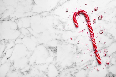 Crushed Christmas candy cane on white marble background, top view. Space for text