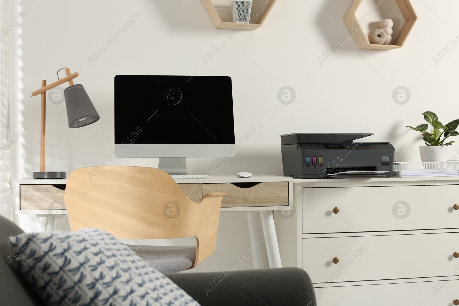 Photo of Stylish workplace with modern computer, printer and lamp