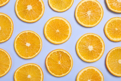 Photo of Slices of juicy orange on light blue background, flat lay