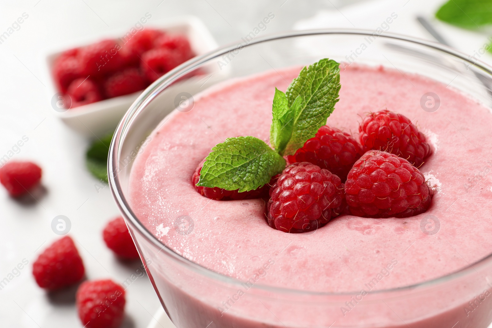 Photo of Delicious raspberry mousse with mint in glass dish, closeup