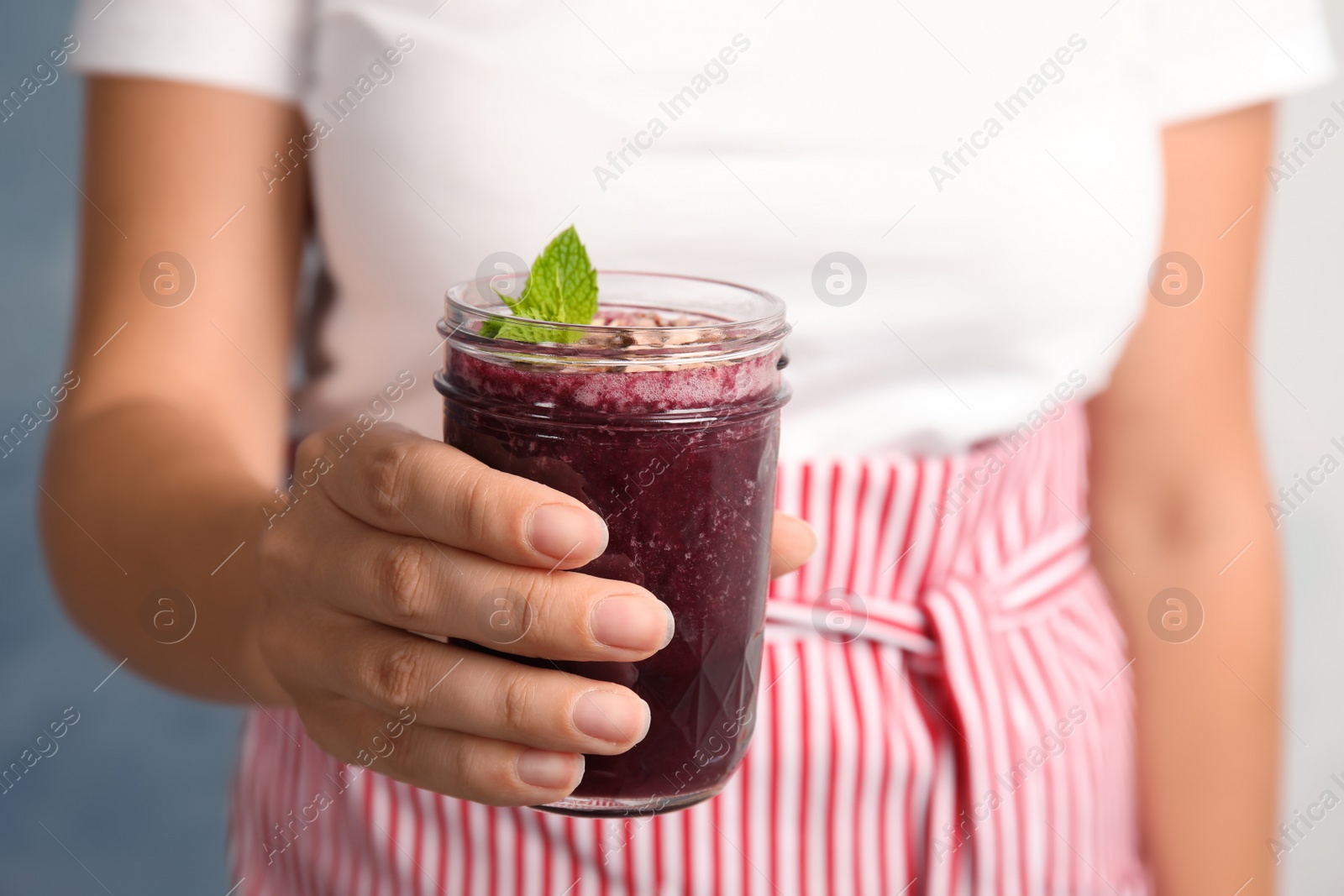 Photo of Woman holding mason jar of delicious acai juice, closeup