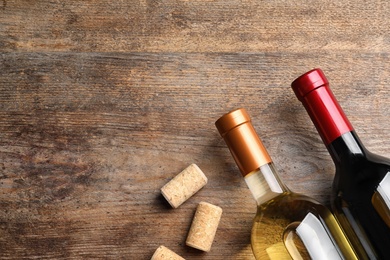 Photo of Flat lay composition with bottles of wine and corks on wooden table. Space for text