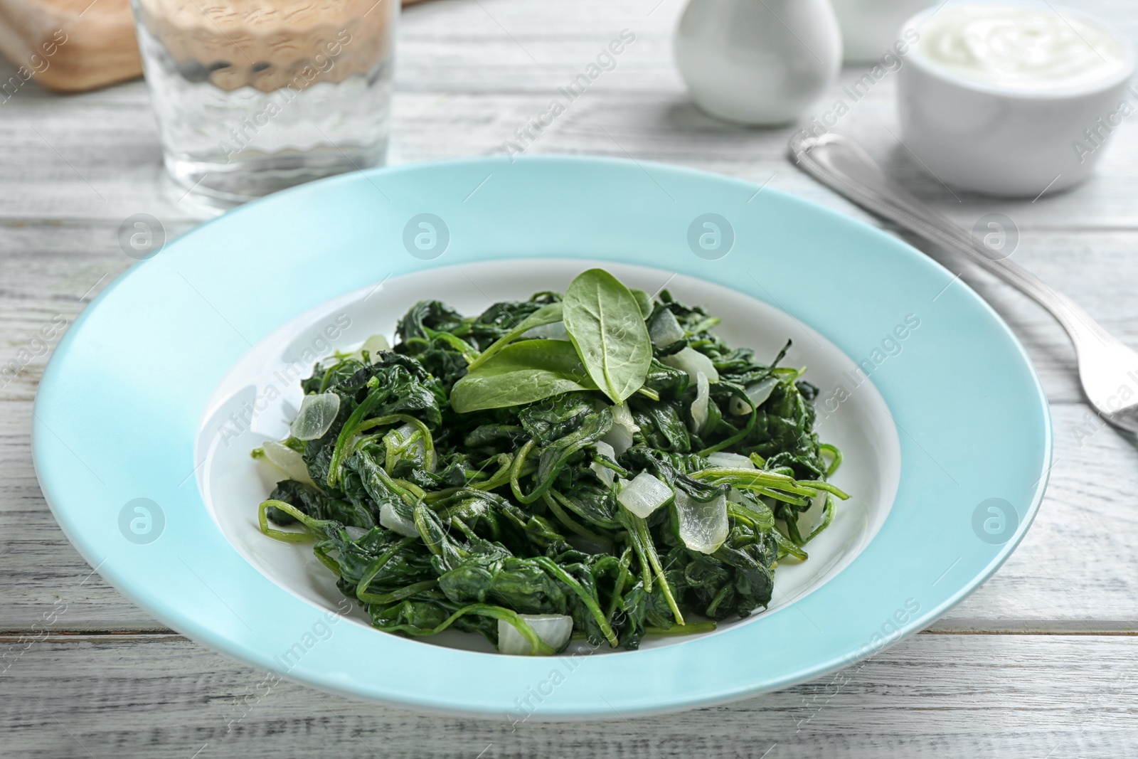 Photo of Tasty cooked spinach served on white wooden table. Healthy food