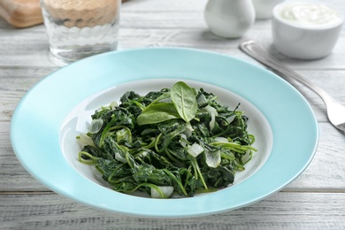 Photo of Tasty cooked spinach served on white wooden table. Healthy food