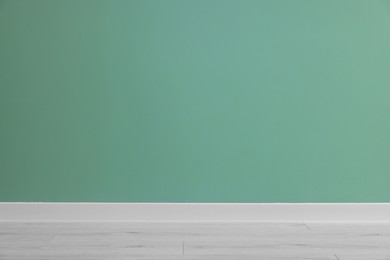 Photo of Beautiful light green wall and wooden floor in clean empty room