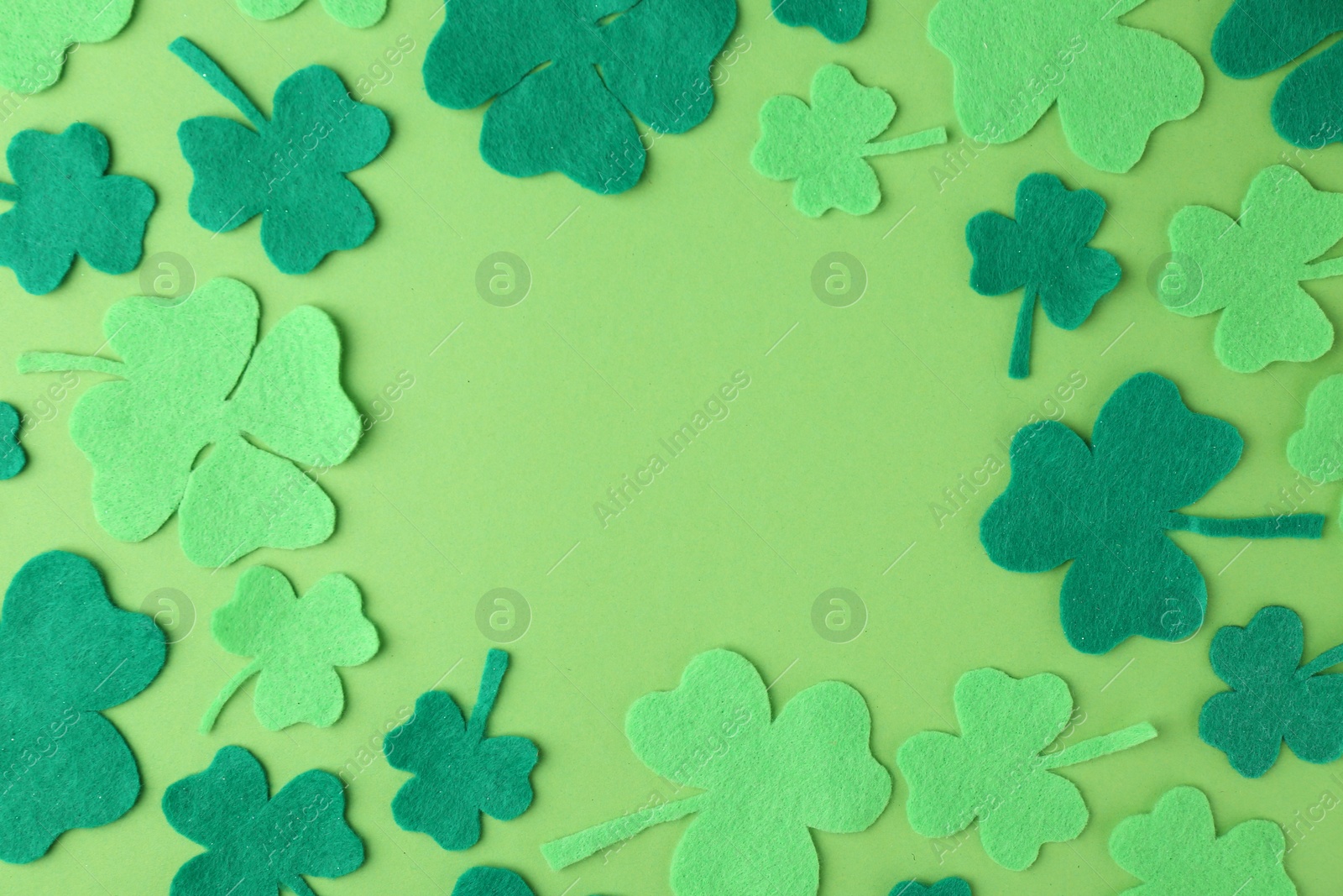 Photo of St. Patrick's day. Frame of decorative clover leaves on green background, flat lay. Space for text