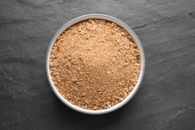 Fresh breadcrumbs in bowl on black table, top view