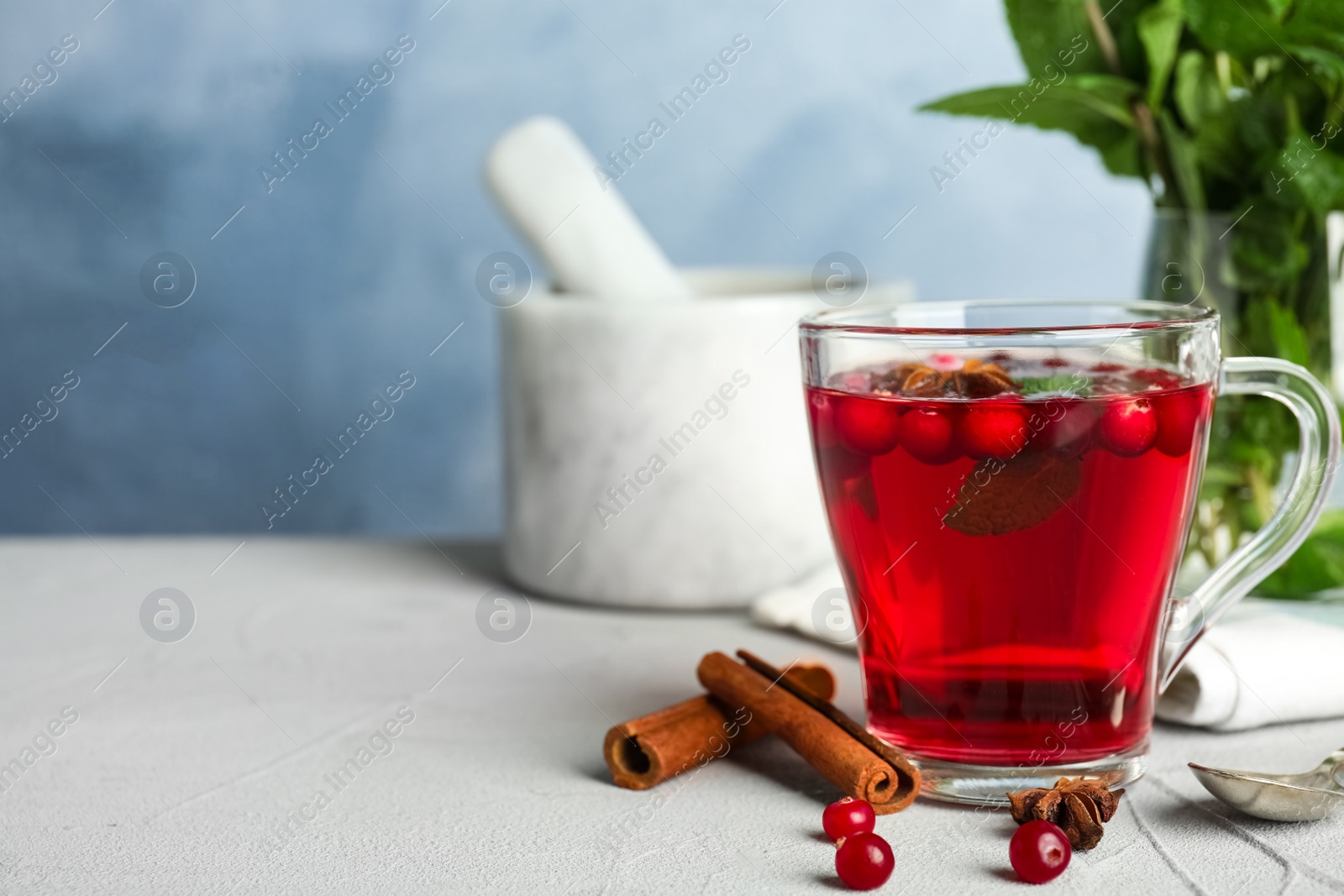 Photo of Tasty hot cranberry tea with mint and fresh ingredients on light table. Space for text