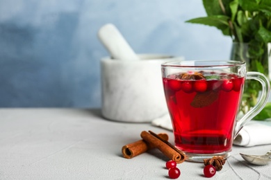 Photo of Tasty hot cranberry tea with mint and fresh ingredients on light table. Space for text