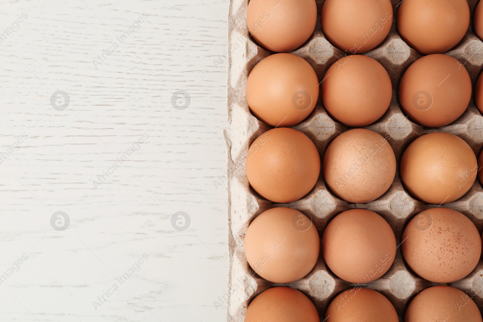 Photo of Raw chicken eggs on white wooden table, top view