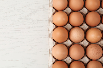 Photo of Raw chicken eggs on white wooden table, top view