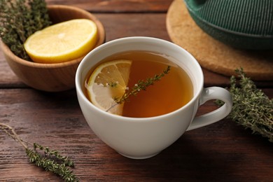 Aromatic herbal tea with thyme and lemon on wooden table